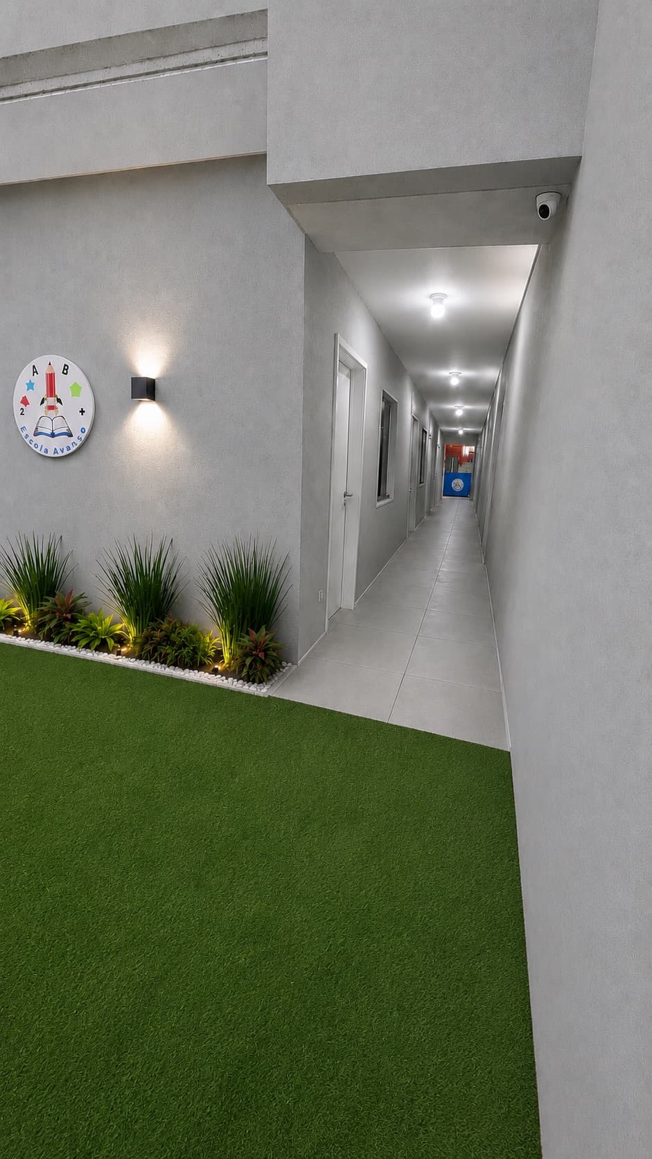 Corredor da Escola Avanço ao lado de jardim interno com plantas e gramado