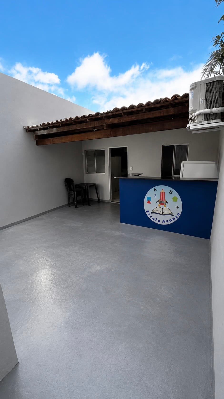 Pátio de recepção da Escola Avanço com balcão azul e área coberta